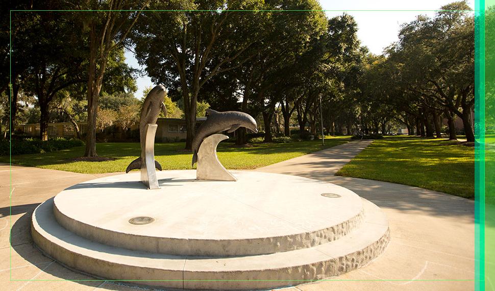 A sunlit picture of the dolphin statues behind the 如何ard Administration Building.